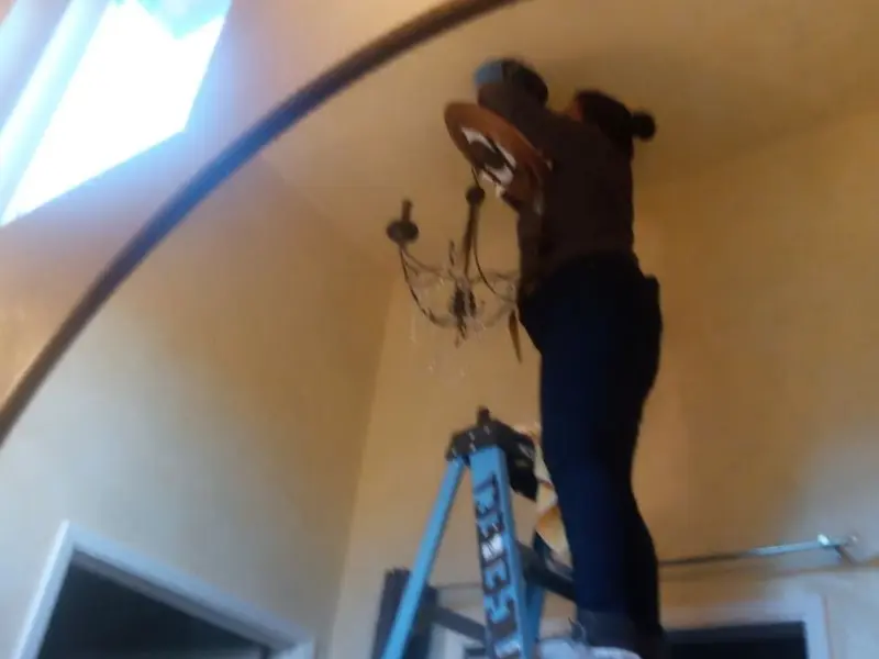Electrician installing a chandelier in a North Alamo residence